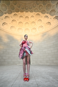 Model wearing a colorful corset dress in an outdoor setting geometric wall design